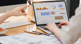 Personas analizando datos en gráficos en la pantalla de una laptop en una oficina