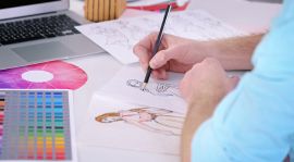 Persona dibujando una ilustración en un cuaderno con referencias de color y diseño