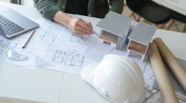 Arquitecto trabajando con planos, maquetas y herramientas de diseño en una oficina